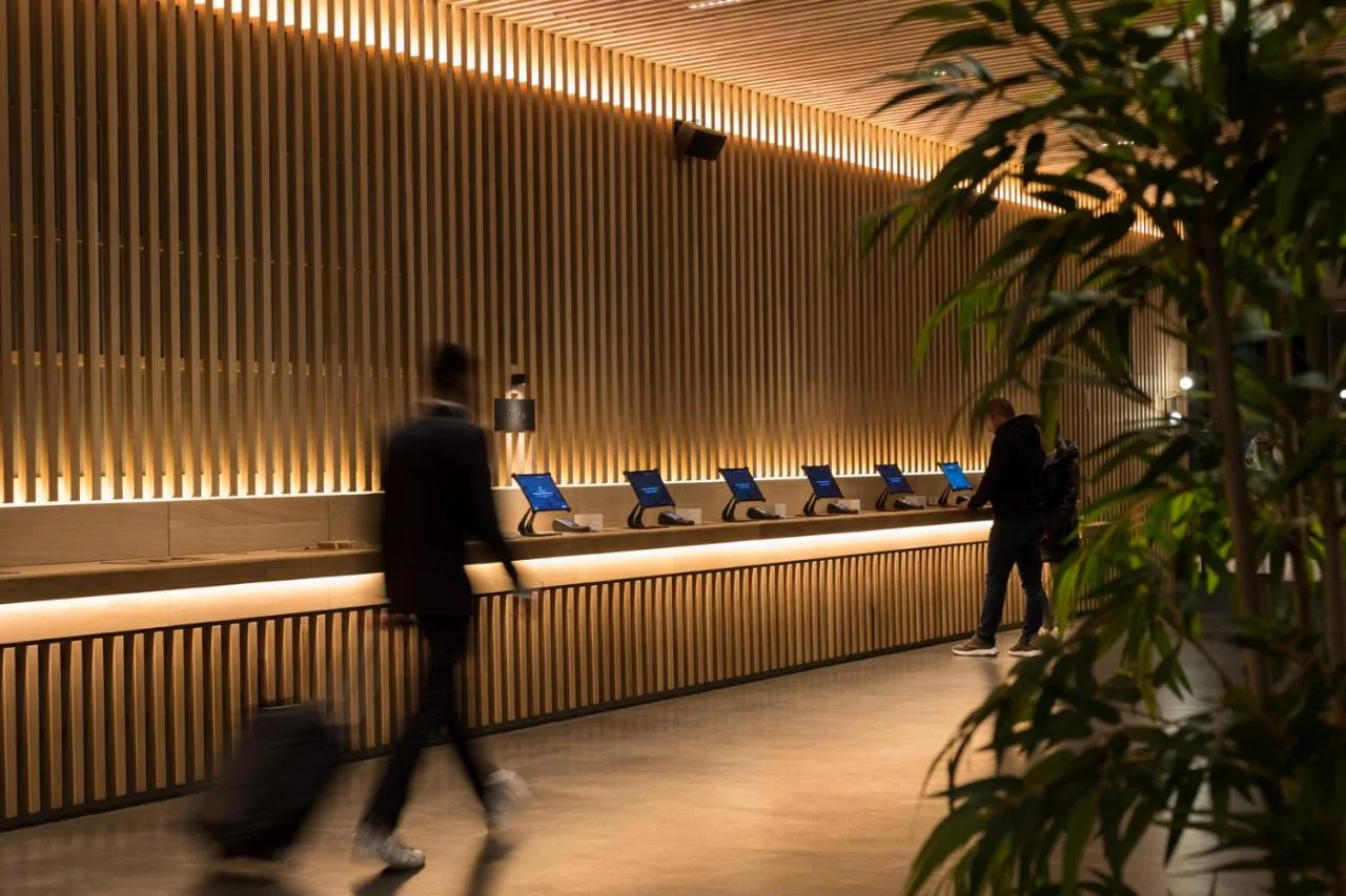 two people walking through a lobby with a row of seats at Zedwell Hotel Piccadilly Circus in London