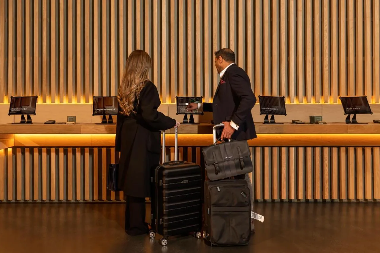 a man and a woman with luggage in front of a counter at Zedwell Hotel Piccadilly Circus in London