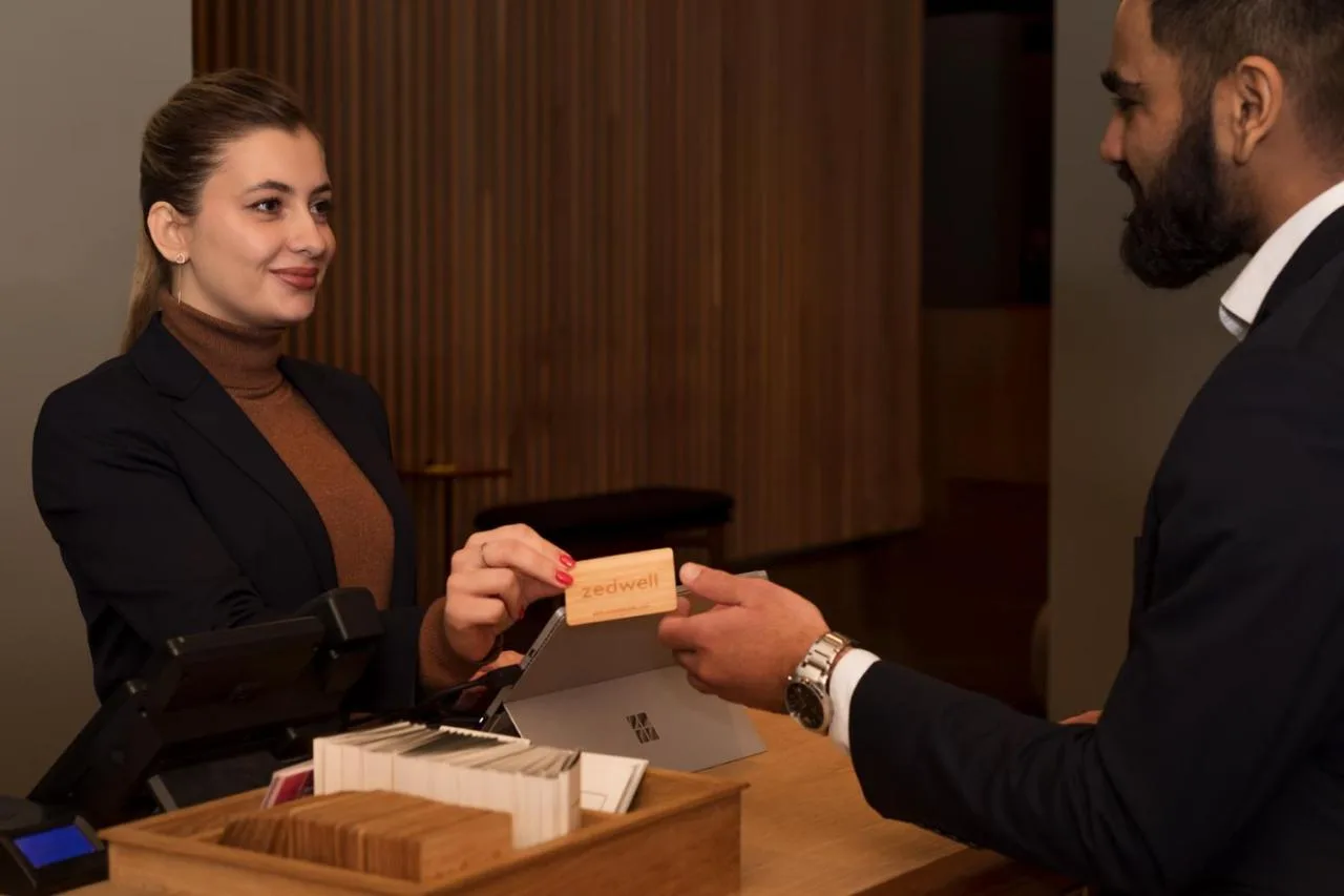 a woman is handing a man a business card at Zedwell Hotel Piccadilly Circus in London